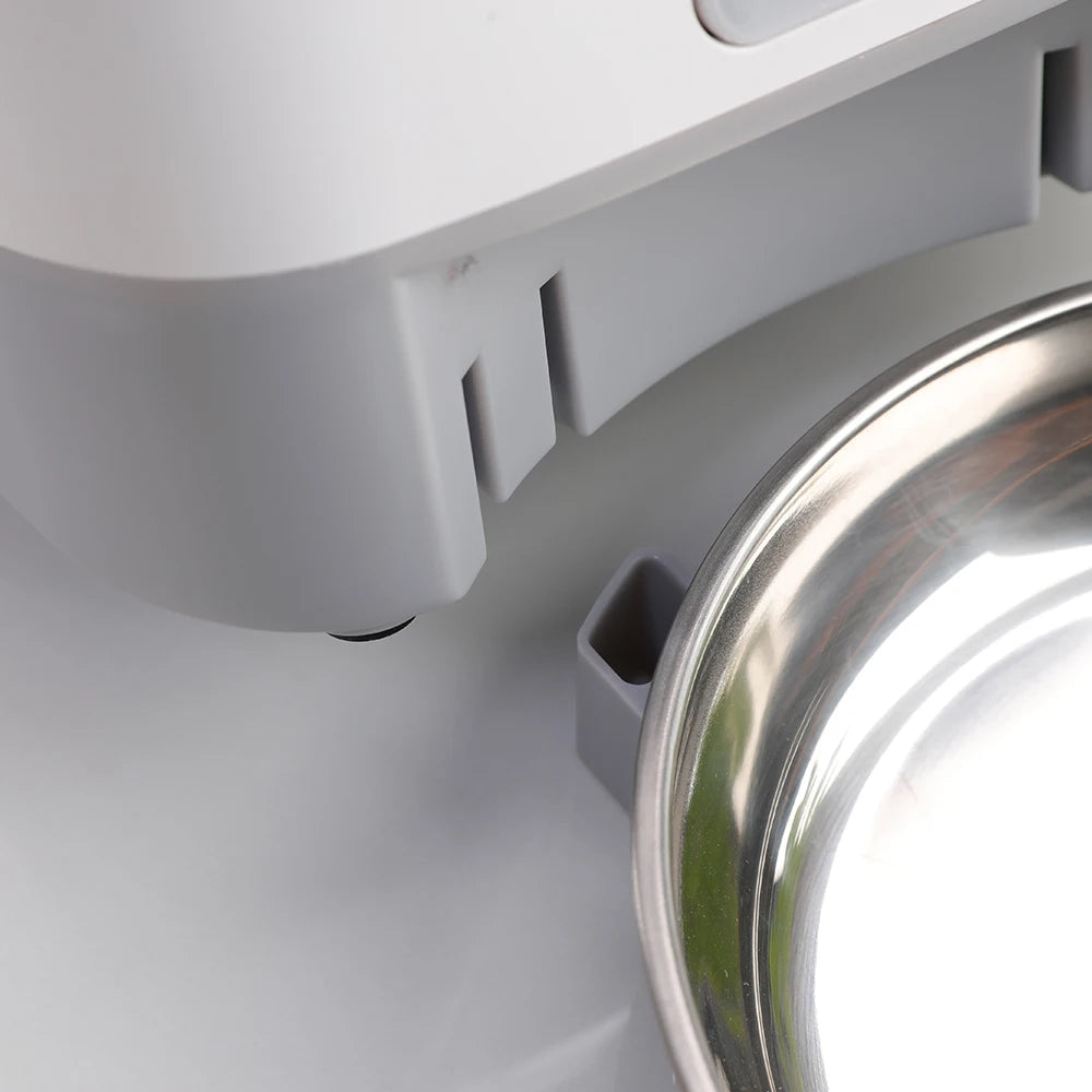 Automatic pet feeder for cats with LCD display and smartphone control, accompanied by a relaxed cat.