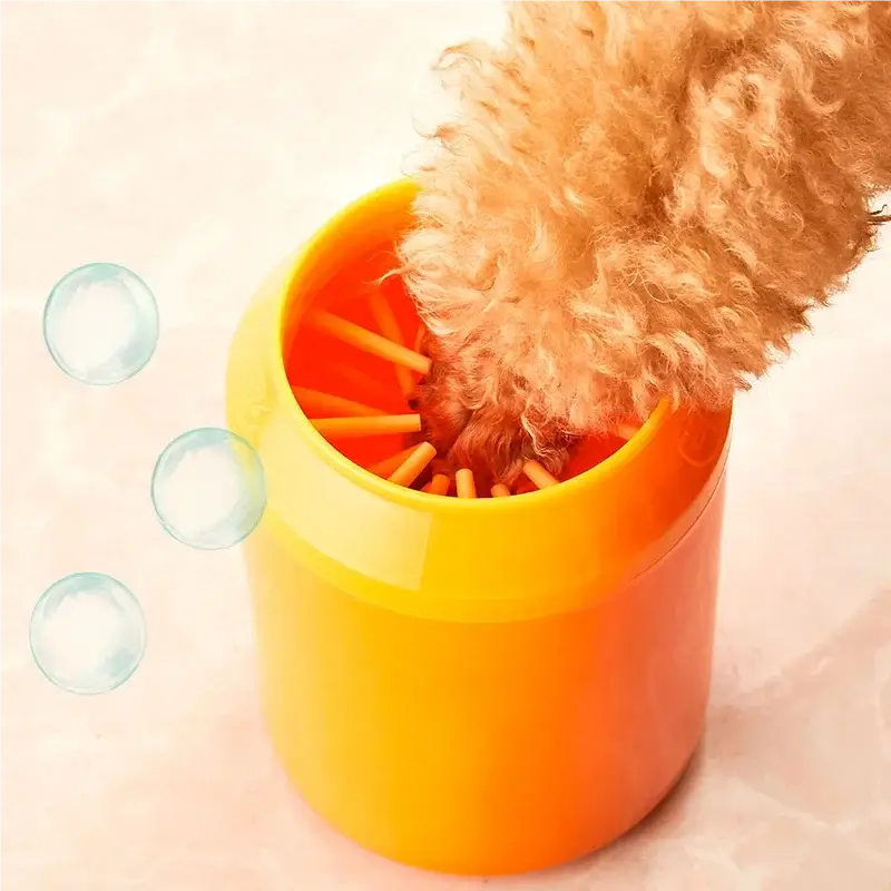 A dog paw being washed in a bright orange pet paw wash cup, with bubbles visible.